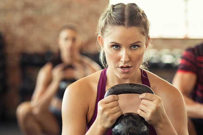 Close-up of a female holding up a Kettlebell during a mixed group class.